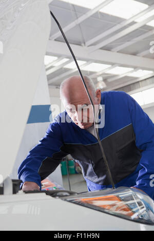 Older Hispanic mechanic repairing car in garage Stock Photo