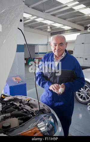 Older Hispanic mechanic working on car in garage Stock Photo