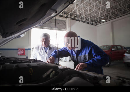 Older Hispanic mechanics repairing car in garage Stock Photo