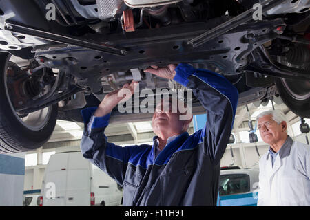 Older Hispanic mechanic repairing car in garage Stock Photo