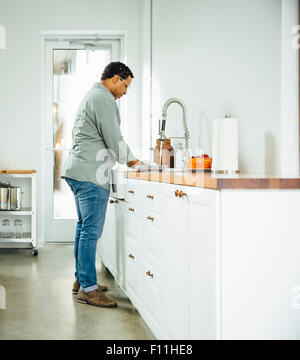 Mixed race man washing dishes in kitchen Stock Photo