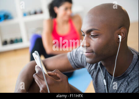 Man listening to earphones in gym Stock Photo