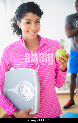 Woman holding apple and scale in gym Stock Photo