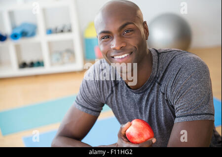 Black man eating apple in gym Stock Photo