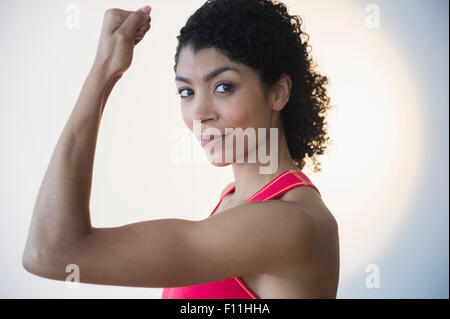 Mixed race woman flexing muscles Stock Photo