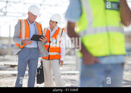Architects using digital tablet at construction site Stock Photo