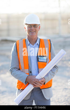 Caucasian architect holding blueprints at construction site Stock Photo