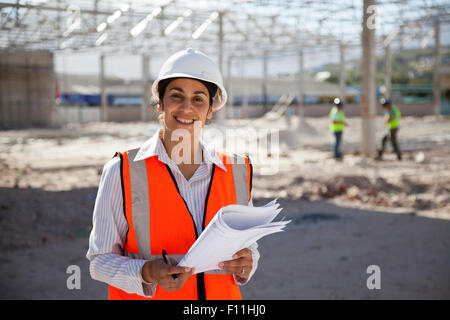 Architect holding blueprints at construction site Stock Photo