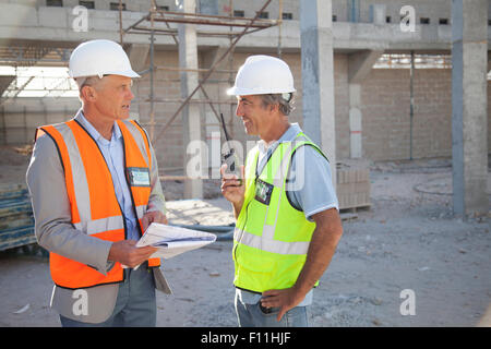 Caucasian architect and construction worker talking at construction site Stock Photo