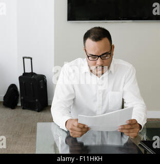 Hispanic businessman reading paperwork in office Stock Photo