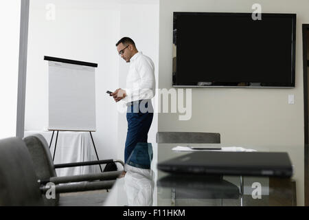 Hispanic businessman using cell phone in conference room Stock Photo