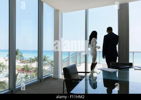 Business people looking out conference room window Stock Photo