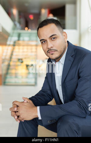 Hispanic businessman sitting in hotel lobby Stock Photo