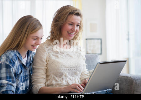 Caucasian mother and daughter using laptop on sofa Stock Photo
