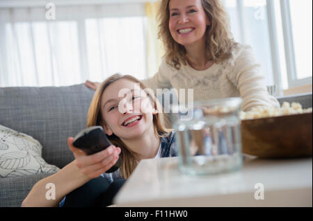 Caucasian mother and daughter watching television on sofa Stock Photo
