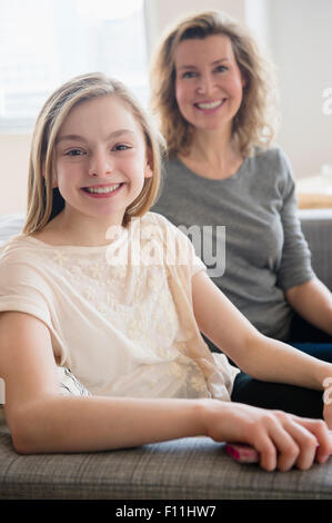 Caucasian mother and daughter smiling on sofa Stock Photo