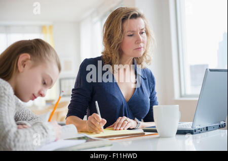 Caucasian mother and daughter working at desk Stock Photo