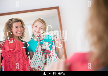 Caucasian mother and daughter examining shirts in mirror