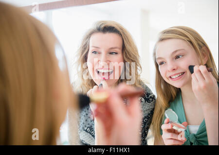 Caucasian mother and daughter applying makeup in mirror Stock Photo
