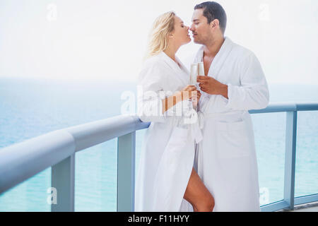 Couple kissing with champagne on balcony Stock Photo
