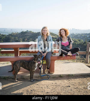 Caucasian women sitting with dog on hilltop