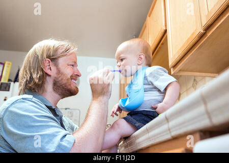 Caucasian father feeding son on kitchen counter Stock Photo