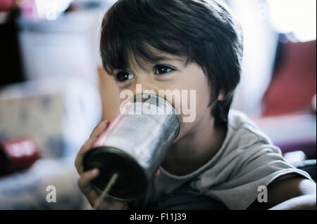 Close up of boy playing with tin can telephone Stock Photo