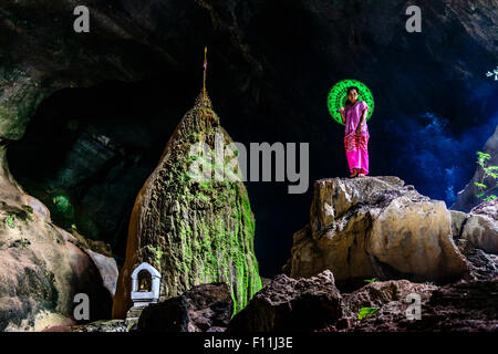 Asian woman standing on rock formation in cave temple Stock Photo