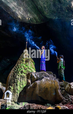 Asian women burning incense on rock formation in cave temple Stock Photo