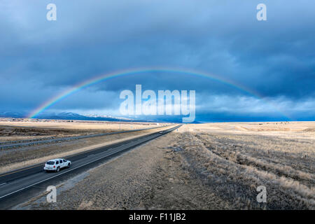 High angle view of car driving to rainbow on remote road Stock Photo