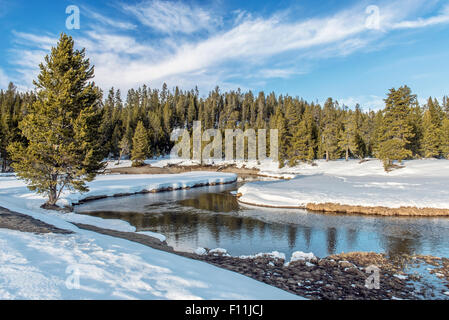 Snowy fields and hills near remote stream Stock Photo