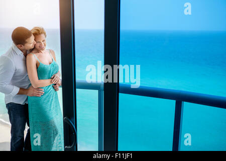Couple kissing on balcony over ocean Stock Photo