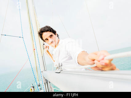 Hispanic man adjusting rigging on sailboat Stock Photo