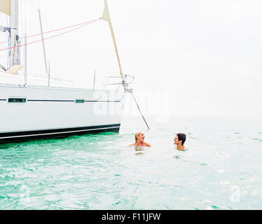 Couple swimming near sailboat Stock Photo