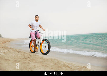 Black man riding bicycle on beach Stock Photo