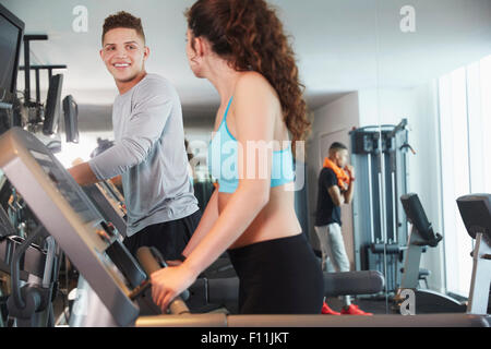 Couple using exercise machines in gym Stock Photo