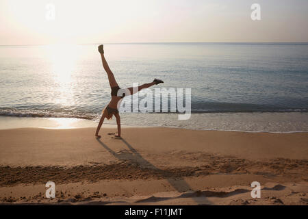 Athlete doing cartwheel on beach Stock Photo