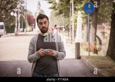 Caucasian man using cell phone on urban street Stock Photo