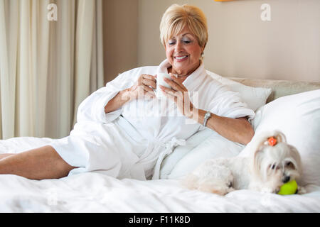 Older Caucasian woman and dog relaxing on bed Stock Photo