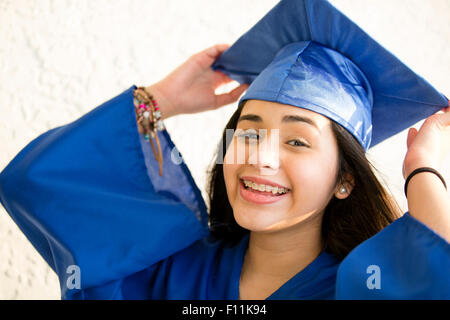Smiling Hispanic girl wearing graduation robe and mortarboard Stock Photo