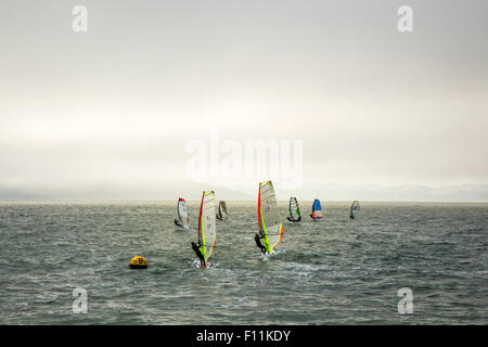 Windsurfers on ocean under cloudy sky Stock Photo
