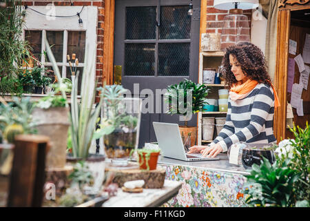 Mixed race employee using laptop in plant nursery Stock Photo