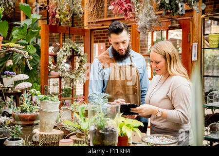 Caucasian employees using digital tablet in plant nursery Stock Photo