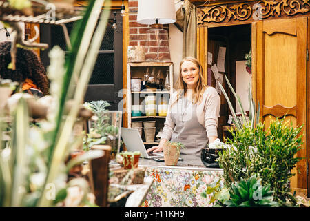Caucasian employee using laptop in plant nursery Stock Photo