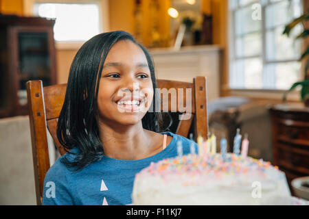 Black girl blowing out candles on birthday cake Stock Photo