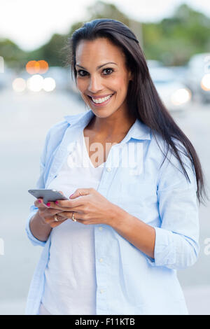 Hispanic woman using cell phone outdoors Stock Photo