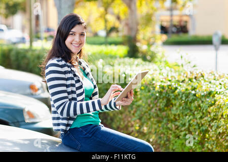 Hispanic woman using digital tablet in parking lot Stock Photo