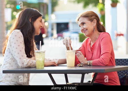 Mother and daughter drinking lemonade at sidewalk cafe Stock Photo