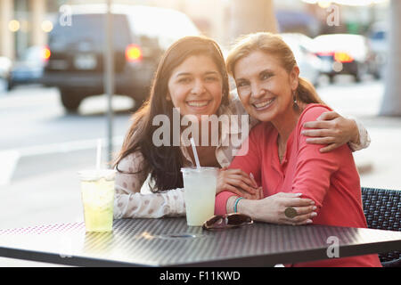 Mother and daughter hugging at sidewalk cafe Stock Photo