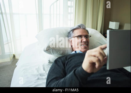 Caucasian man using digital tablet in bed Stock Photo